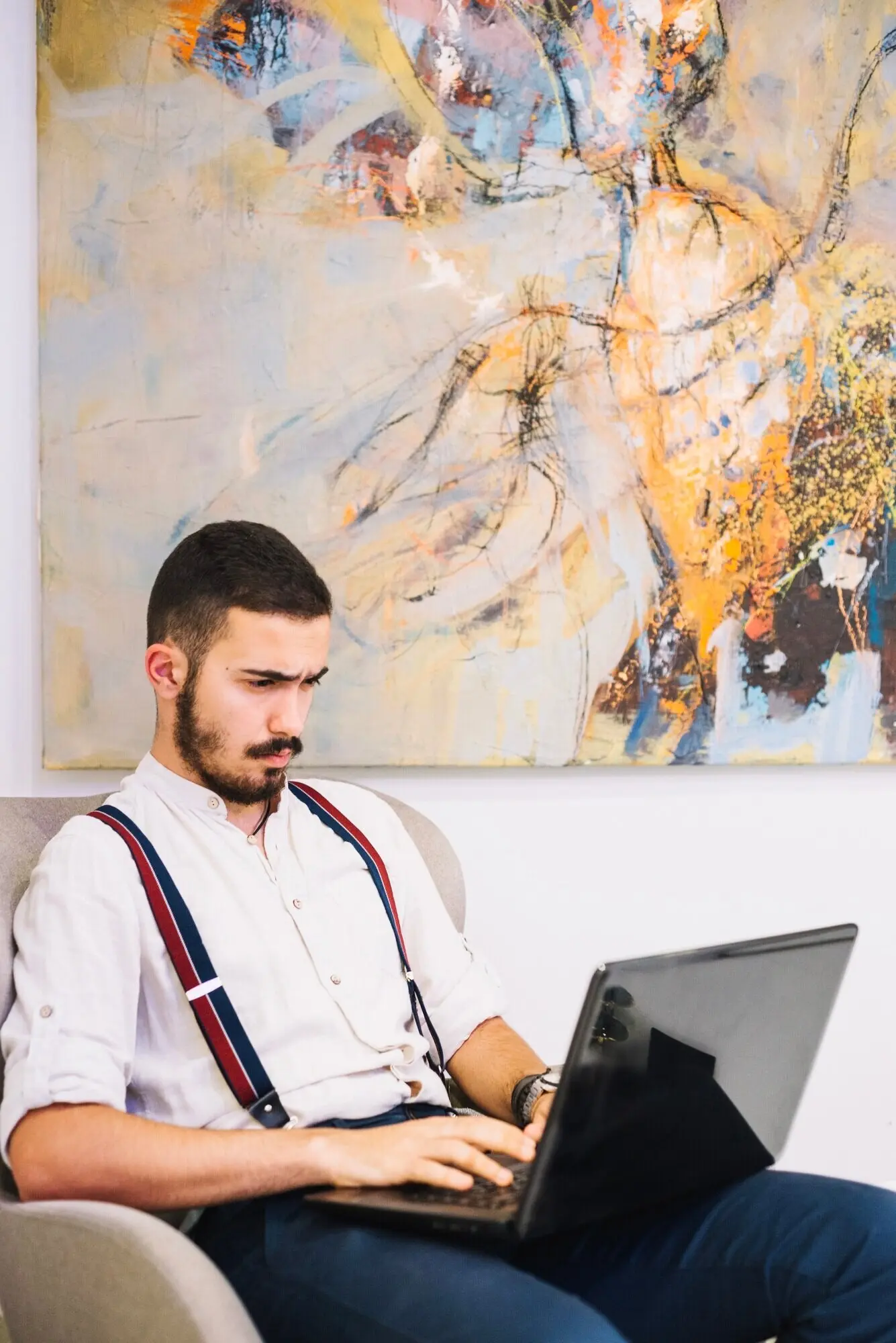 Нахмурившийся мужчина, пользующийся ноутбуком